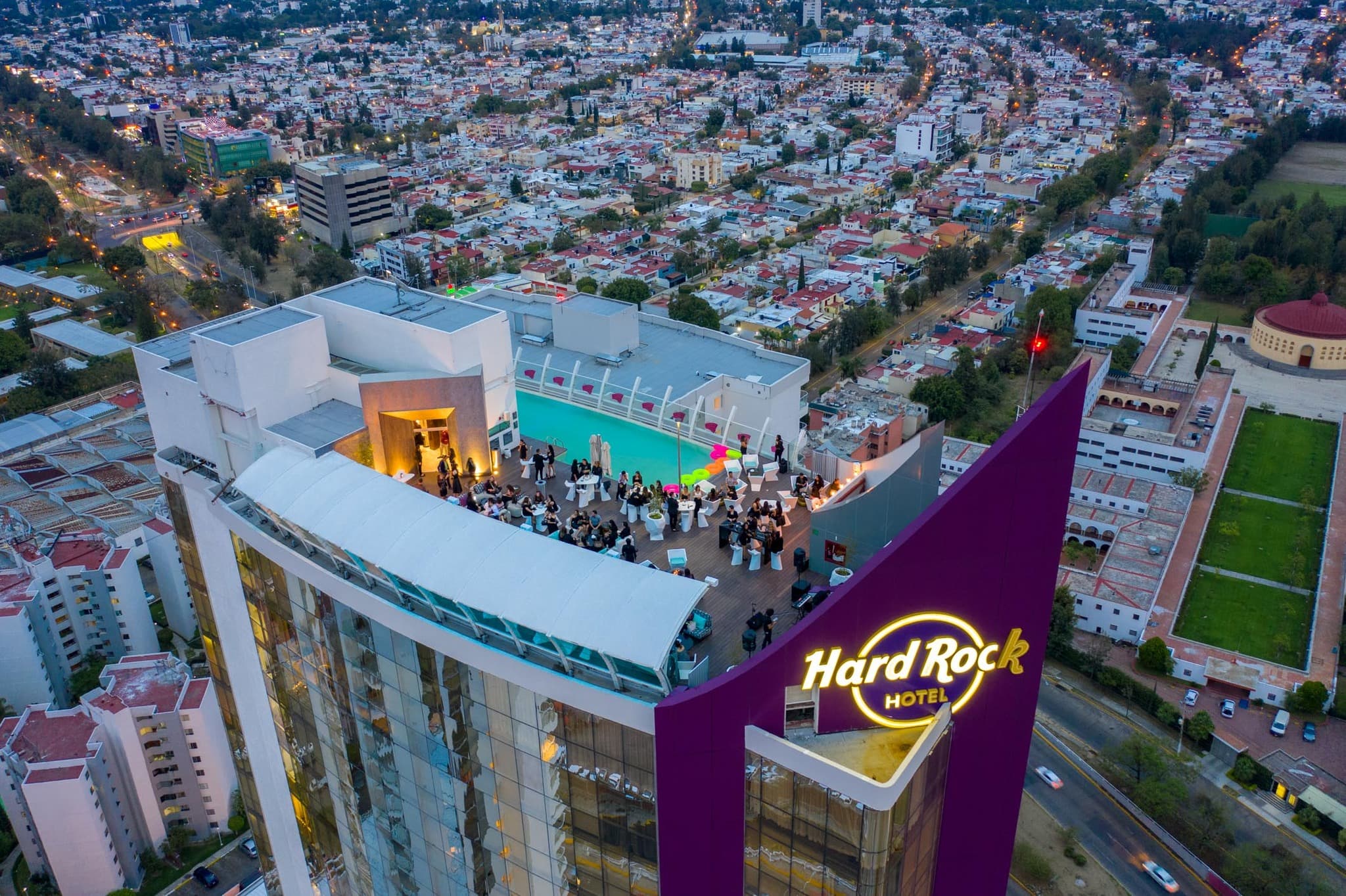 Terraza del Hard Rock Hotel con piscina y personas en un evento con vista urbana.