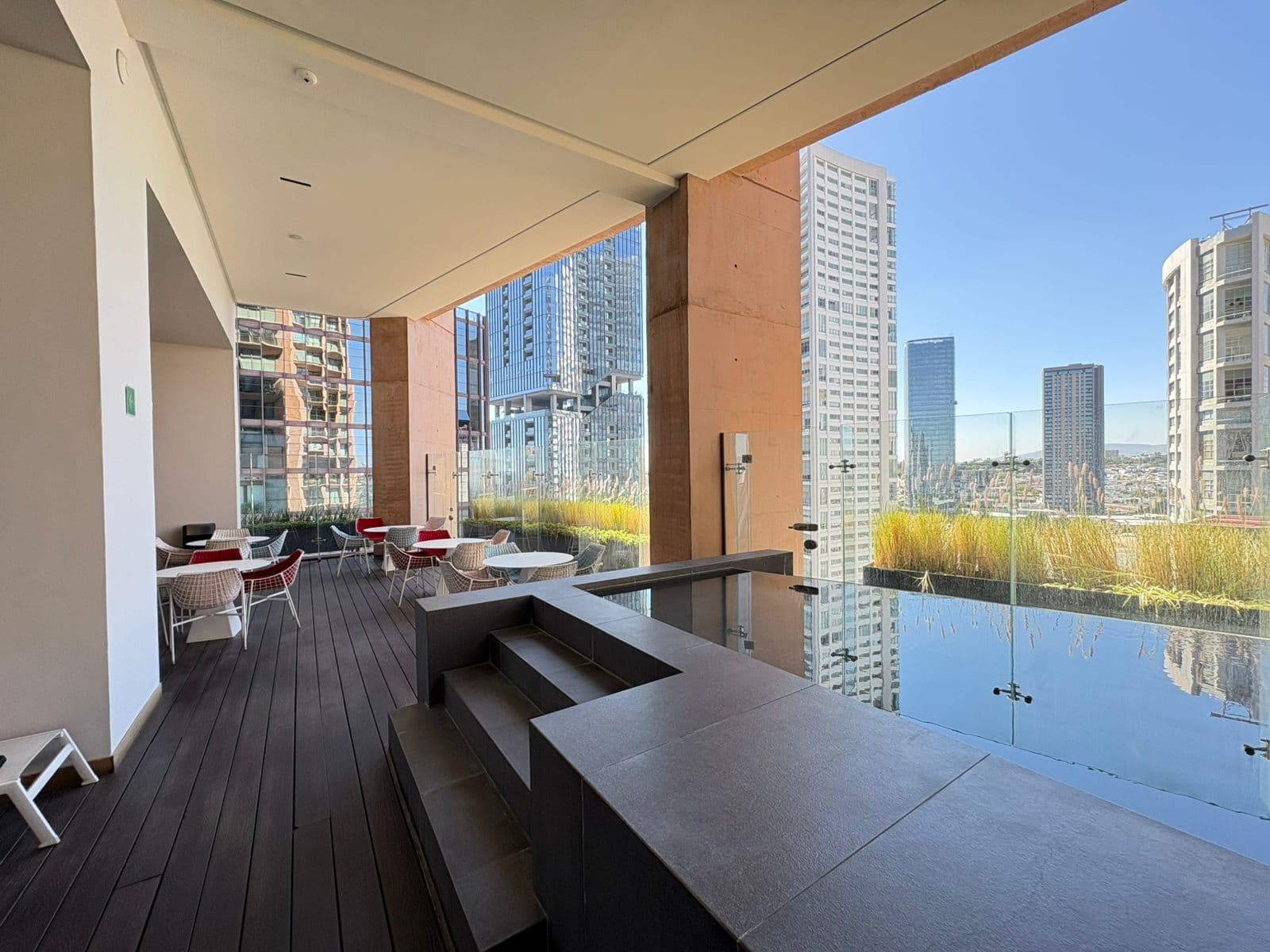Terraza moderna con piscina, mobiliario exterior y vistas panorámicas a rascacielos de la ciudad.