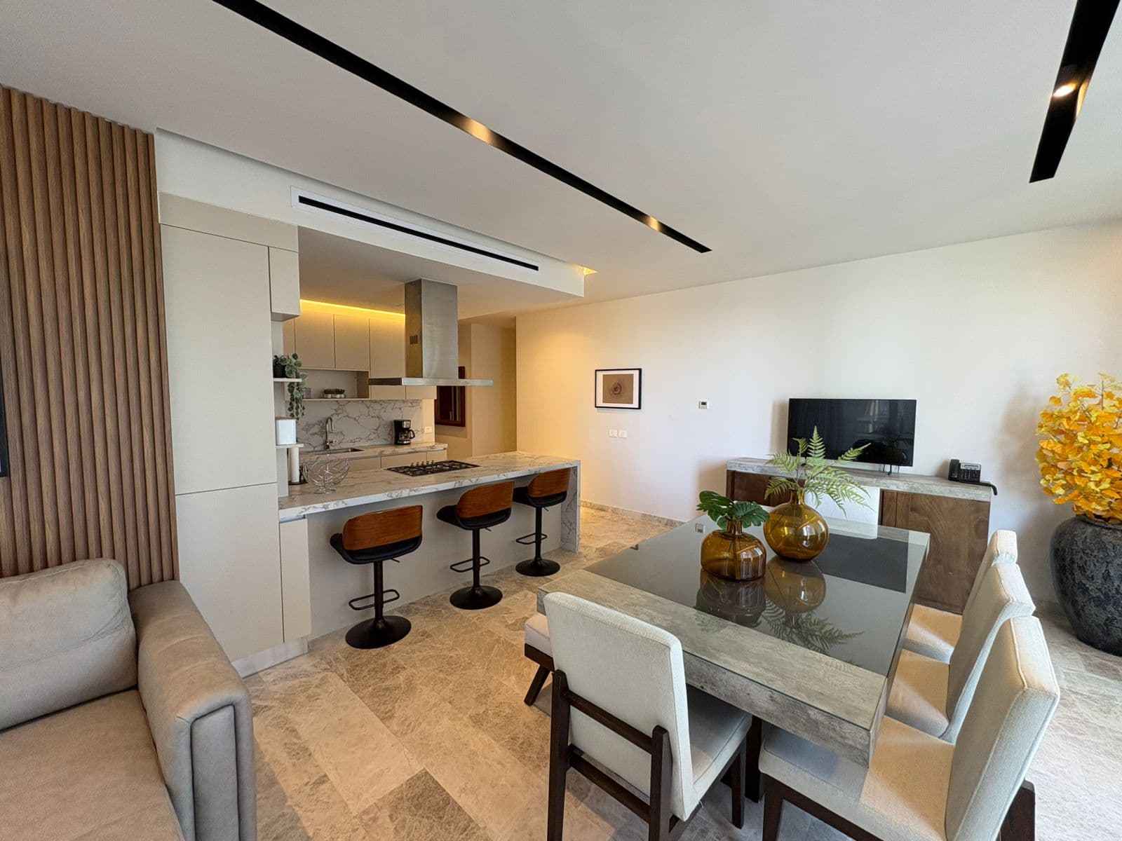 Apartamento moderno con isla de cocina de mármol, mesa de comedor y acabados elegantes.